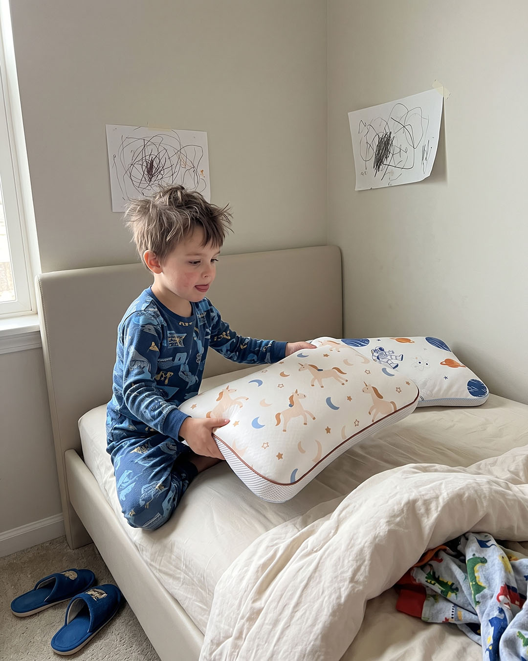 Enfant installant sur son lit deux oreillers Lunillow, housses licorne et astronaute